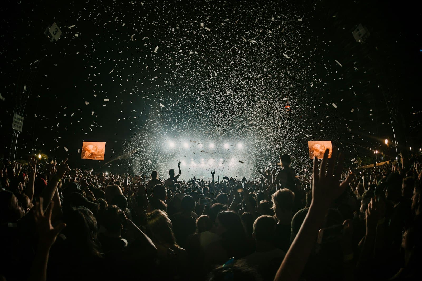 A night festival crowd under a sky of drifting lights